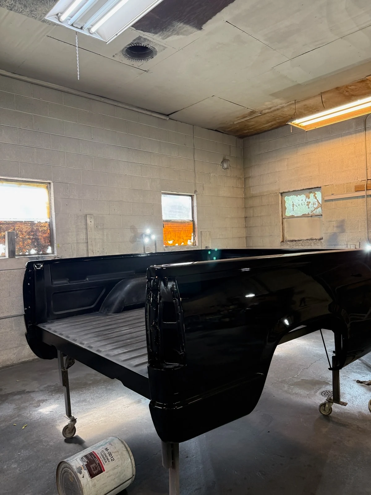 Same detached pickup truck bed after refinishing in a deep glossy black automotive finish